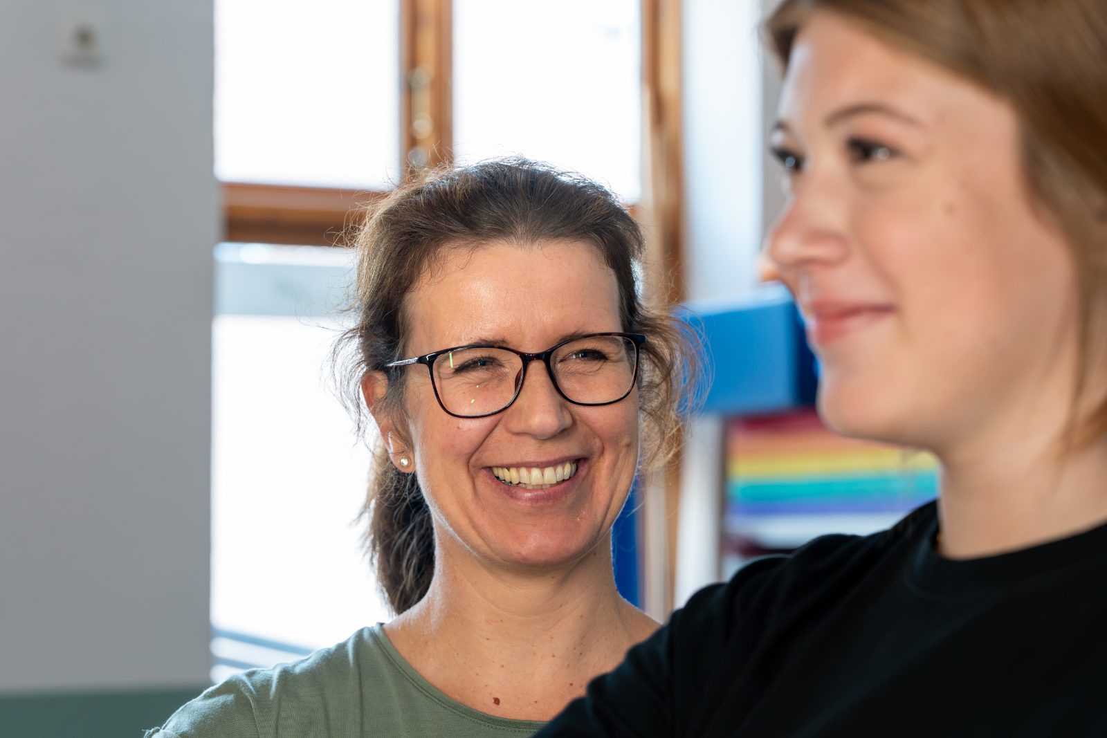 Jessica Robinson lacht gemeinsam mit einer jungen Patientin in ihrer Praxis