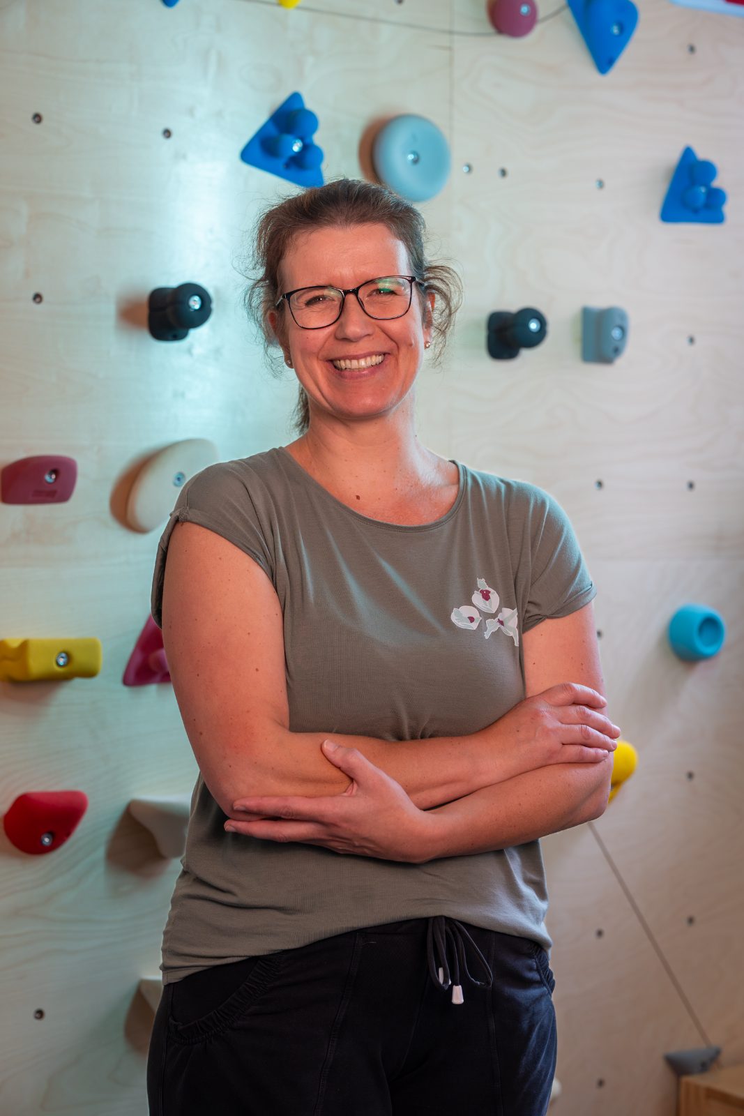 Portrait von Jessica Robinson vor der Kletterwand ihrer Praxis