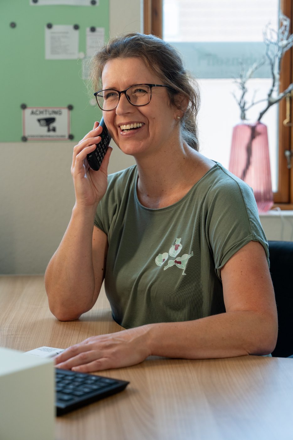 Jessica Robinson telefoniert lächelnd in ihrer Praxis
